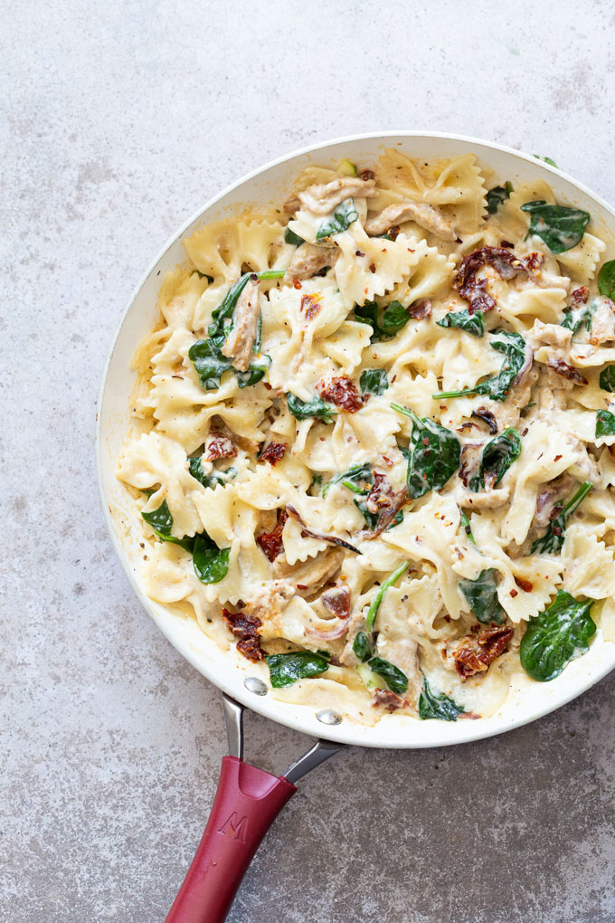 sun-dried tomato pasta with garlic soy curls in a white pan on a concrete counter top 