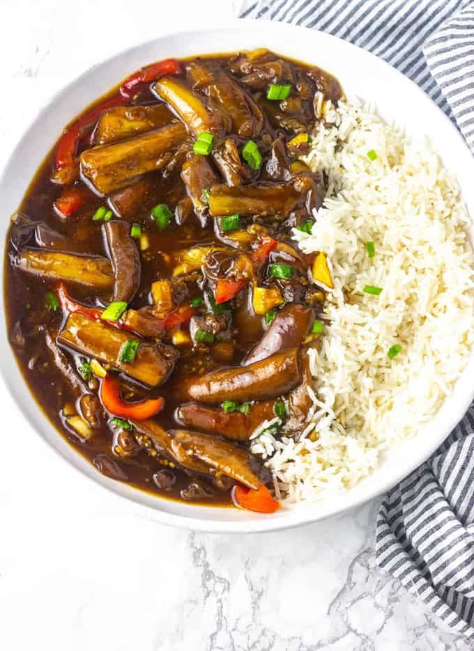 Chinese Eggplant in Garlic Sauce with rice in a white plate on a marble counter top 