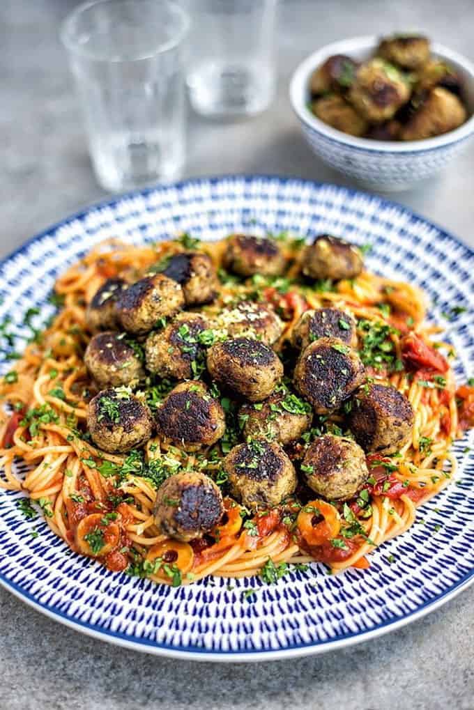 Vegan Aubergine Meatballs with Spaghetti on a blue and white plate on a concrete counter top 