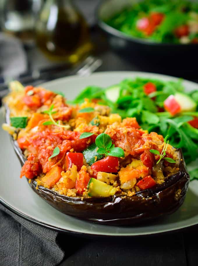 Vegan Stuffed Eggplant on a grey plate with a green salad on the side 