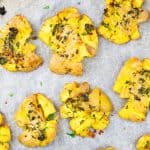 close up photo of garlic smashed potatoes on a baking sheet lined with parchment paper