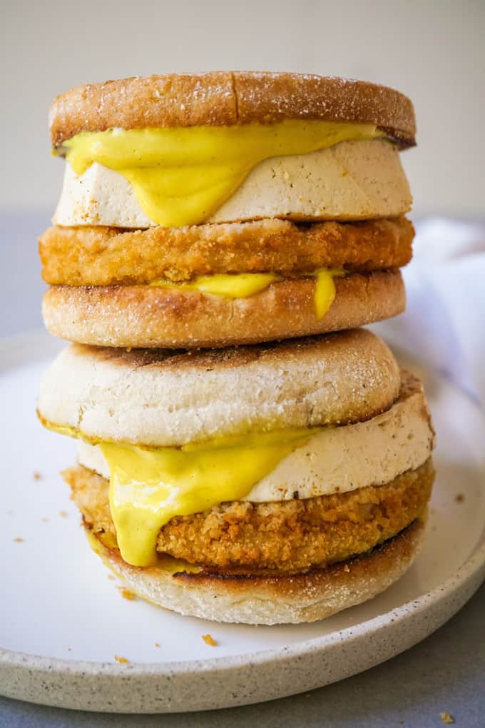 a stack of two vegan chick'n Benedict sandwiches with vegan Hollandaise on a white plate 