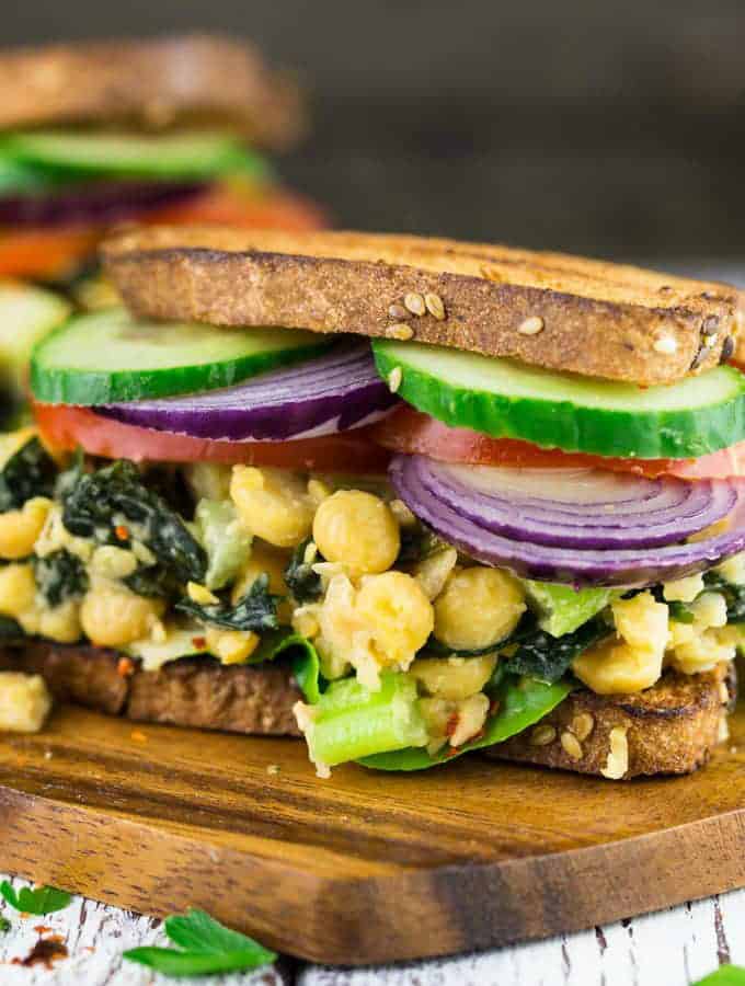 two vegan tuna sandwiches with chickpeas on a wooden board with a grey background