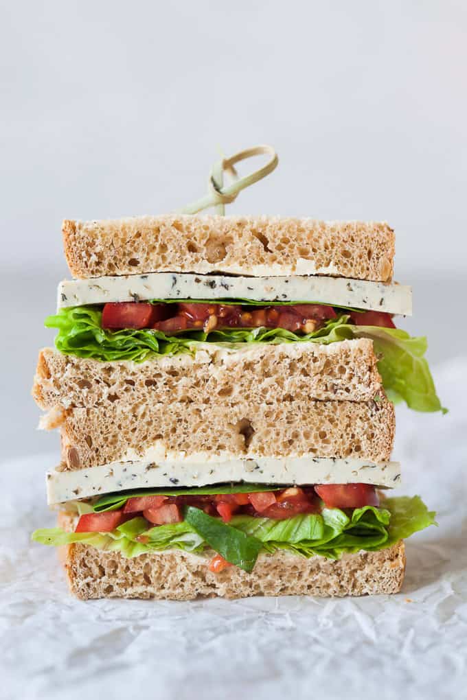 a stack of two basil tofu tomato vegan sandwiches with a white background