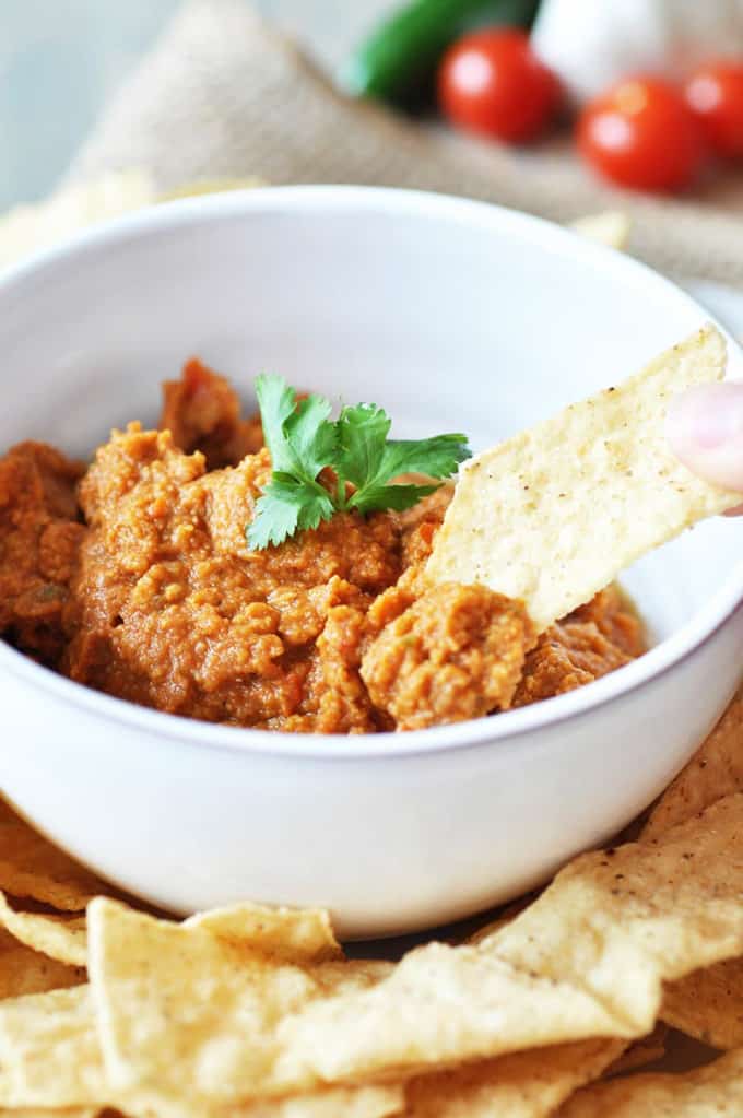 Spicy Mexican Hummus in a white bowl with nacho chips on the side 