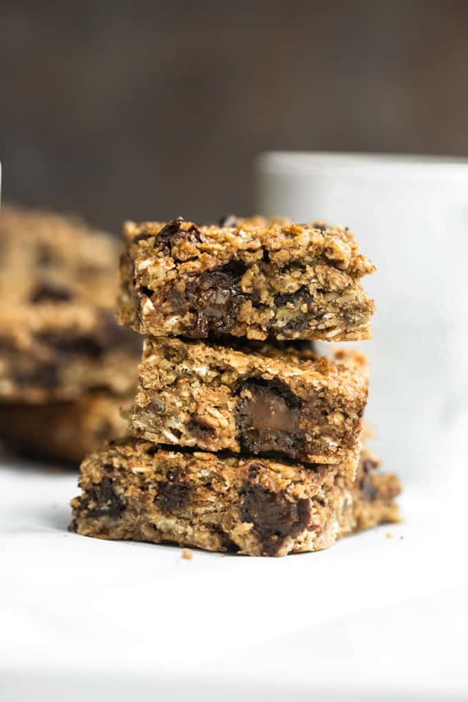 a pile of three vegan granola bars with a white mug in the background