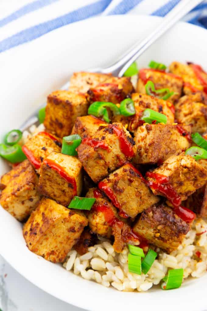 close-up photo of marinated tofu with brown rice in a white bowl