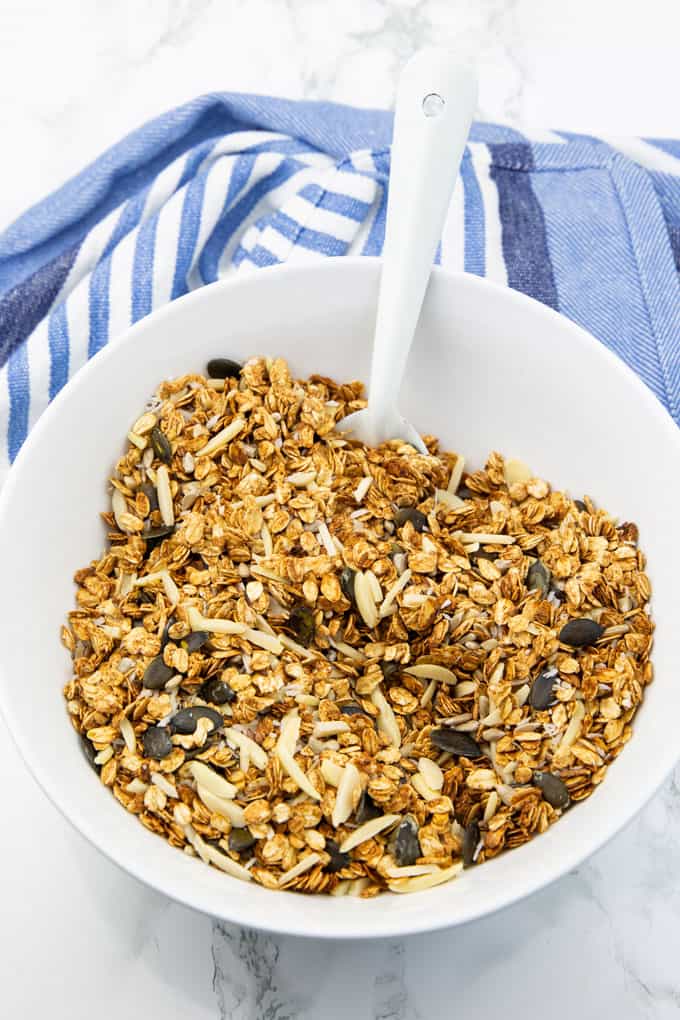 Vegan Cereal in a white bowl on a marble countertop with a blue tablecloth in the background