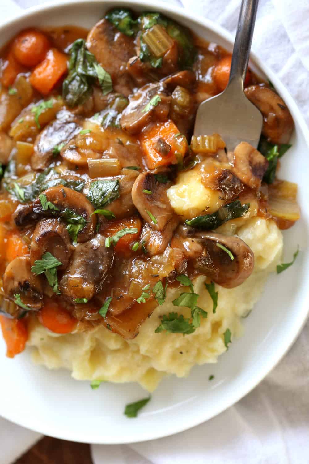 Vegan Mushroom Bourguignon with Cauliflower in a white bowl with a fork