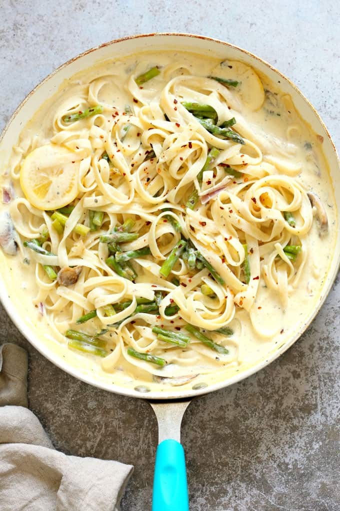 Vegan Lemon Asparagus Pasta in a pan with a blue handle on a concrete countertop