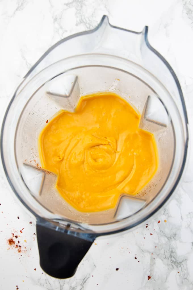 Vegan nacho cheese sauce in a blender on a marble countertop