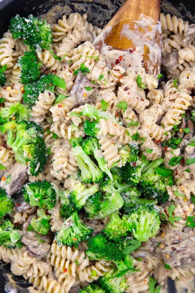 close-up photo of broccoli pasta with mushrooms with a wooden spoon 