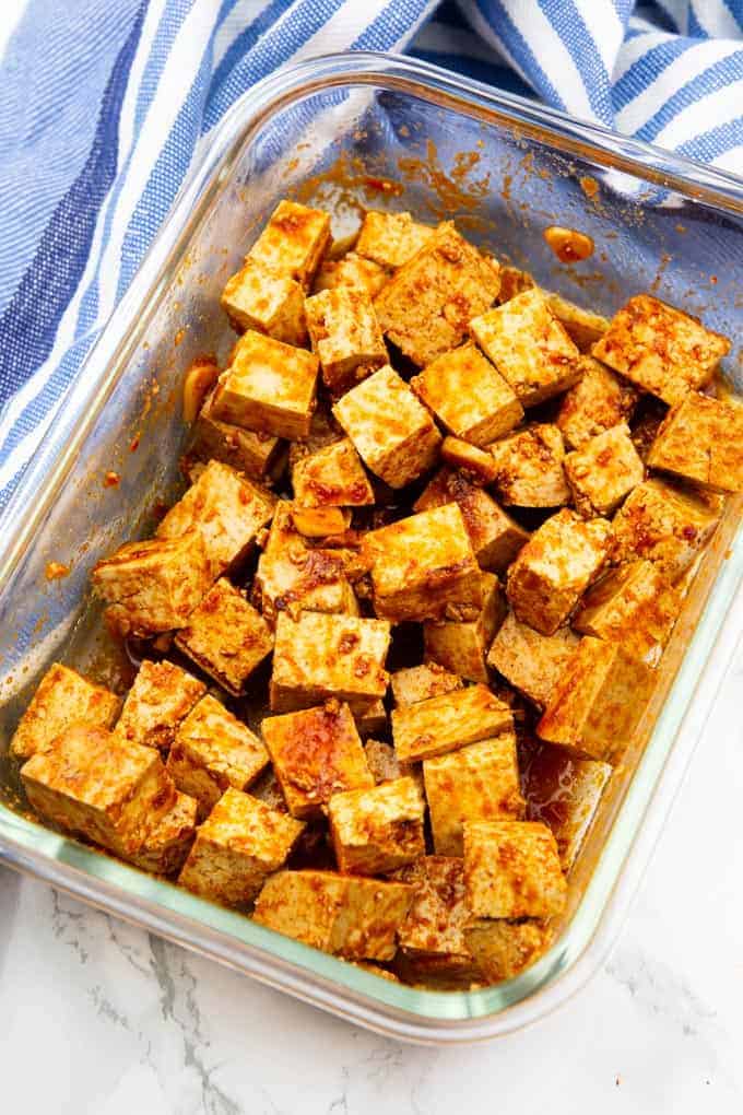 marinated tofu cubes in glass bowl on a marble countertop 