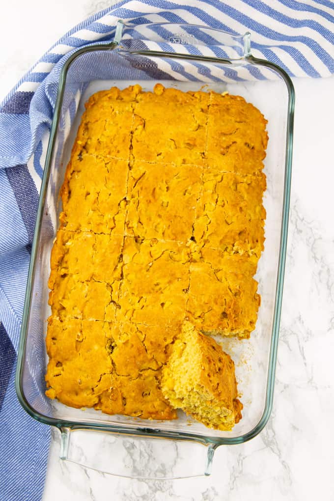 Vegan Cornbread in a glass baking dish on a marble countertop with a white and blue dishcloth 