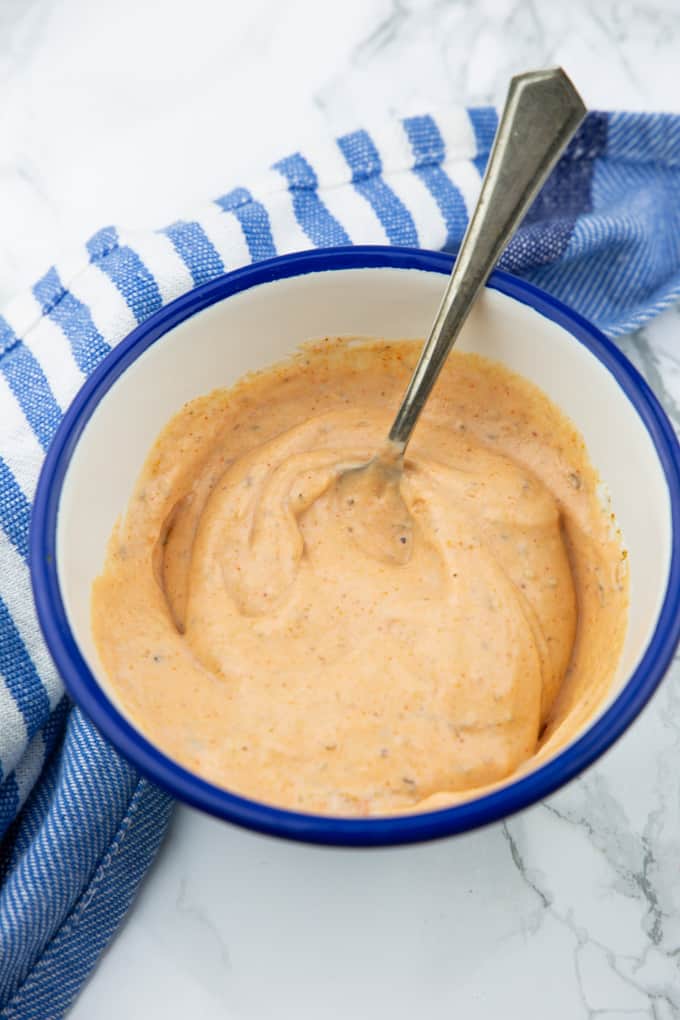 Sweet Potato Fries Dipping Sauce in a small blue and white bowl with a spoon on a marble countertop 