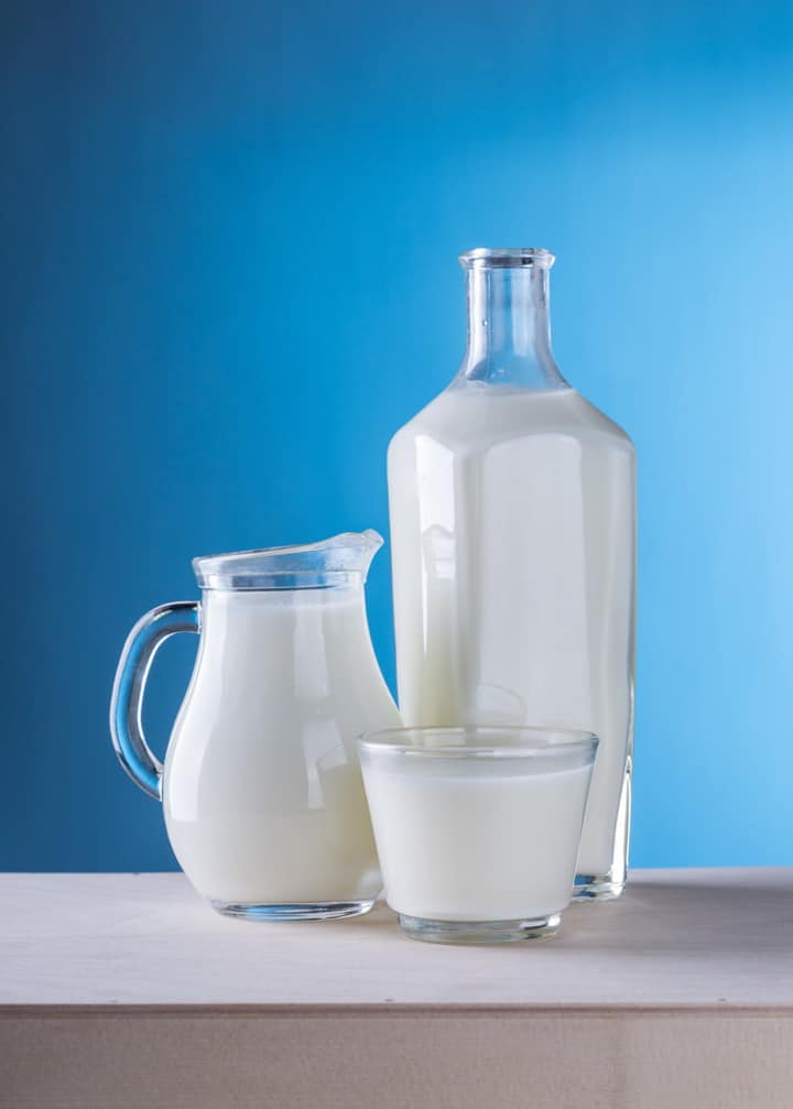 a glass, a bottle, and a milch pitcher with a blue background 