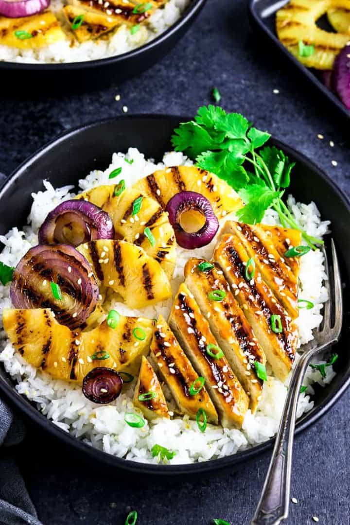  a Grilled Pineapple Teriyaki Bowl on a black countertop with a fork on the side 