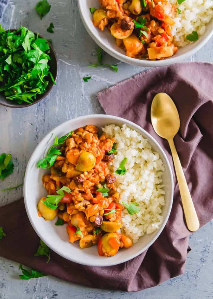 two bowls of vegan picadillo with rice on a concrete countertop 