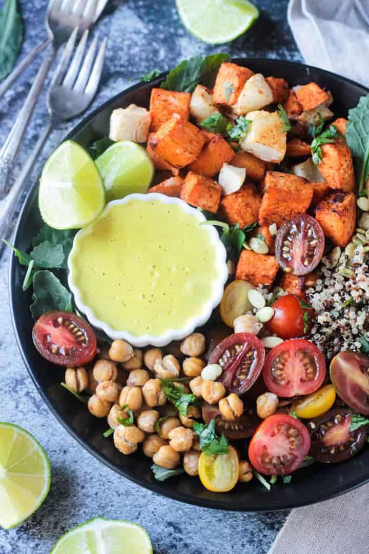 sweet potato cubes, quinoa, chickpeas, and cherry tomatoes in a black bowl with a fork on the side 