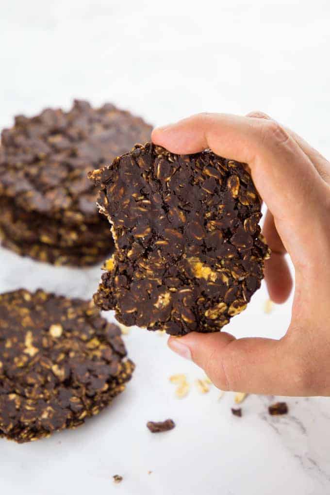 a hand holding a chocolate no bake cookie with more cookies in the background 