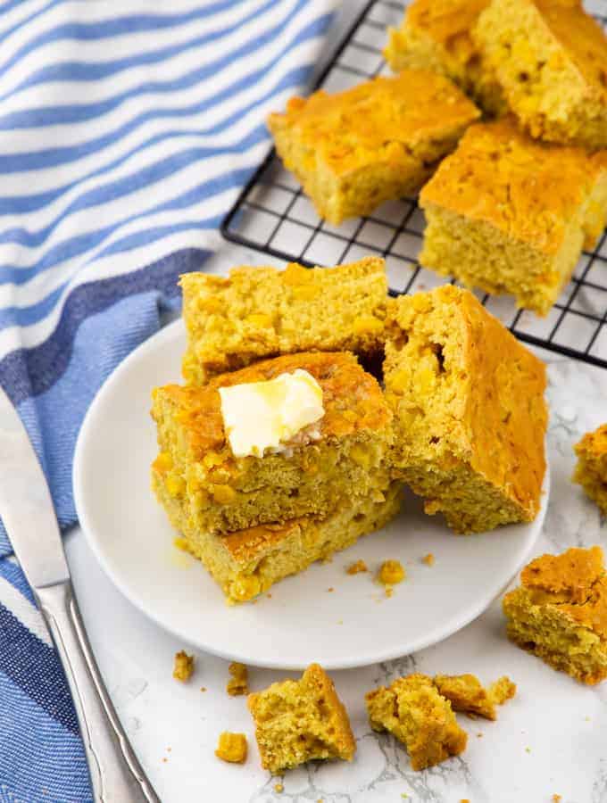 several squares of vegan cornbread on a plate with a cooling rack in the background 