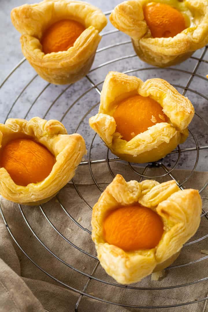 five Apricot Pudding Cupcakes on a cooling rack 