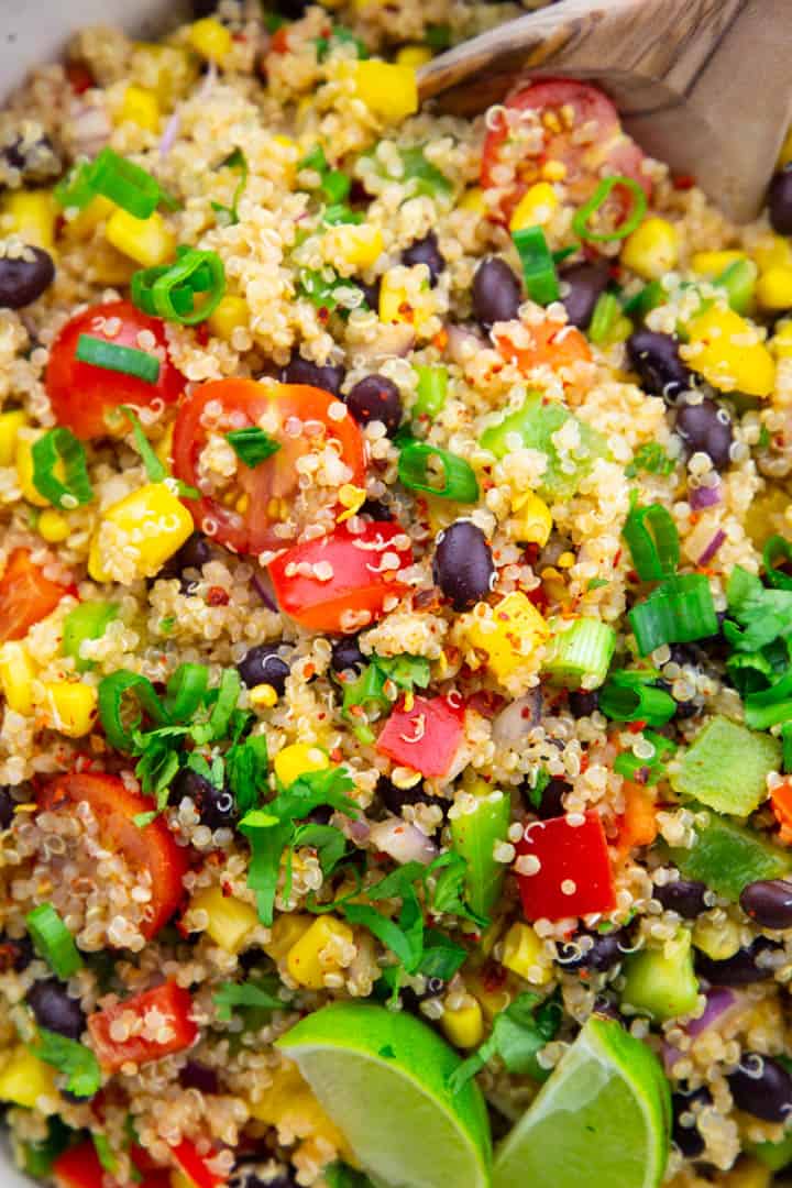 a close-up photo of Mexican quinoa salad with black beans, corn, and two lime wedges 