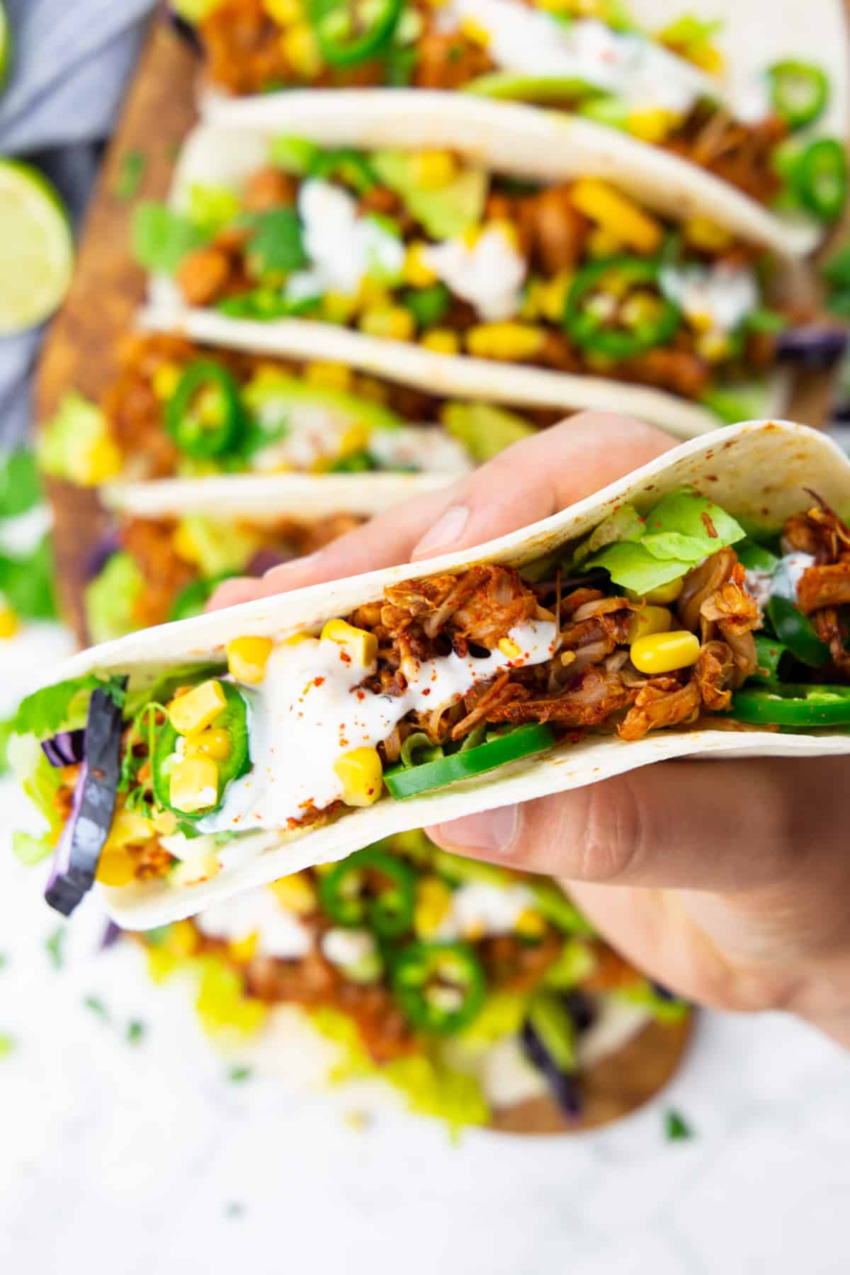 a hand holding a taco filled with pulled jackfruit 