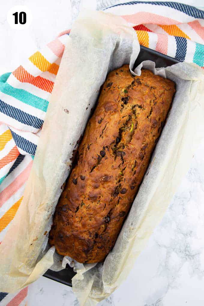 a vegan zucchini bread in a loaf form lined with parchment paper 