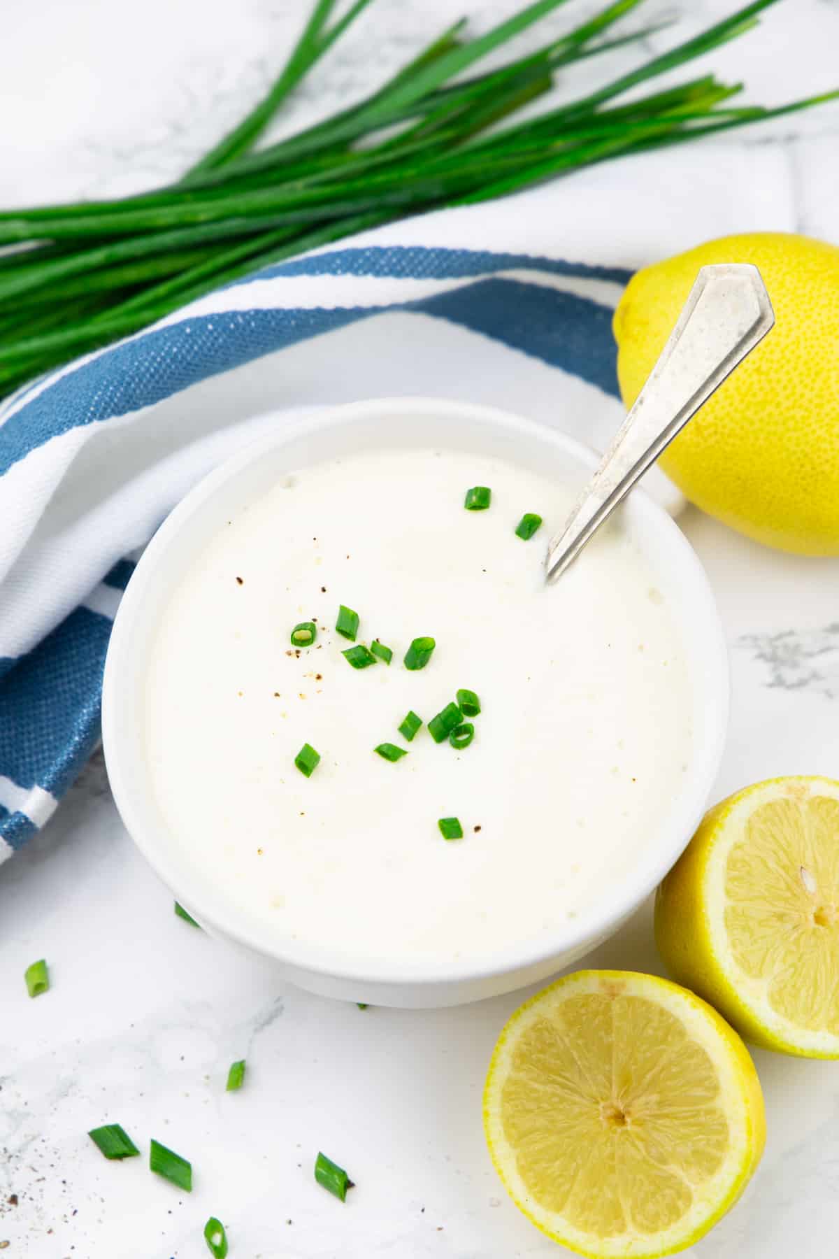 a white bowl with sour cream with lemons and chives on the side 