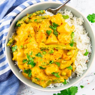 Vegetable korma with rice in a grey bowl on a marble countertop