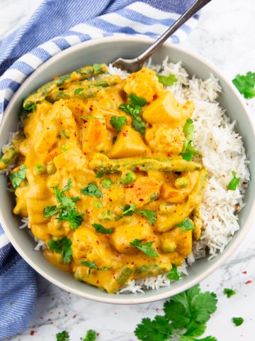 Vegetable korma with rice in a grey bowl on a marble countertop