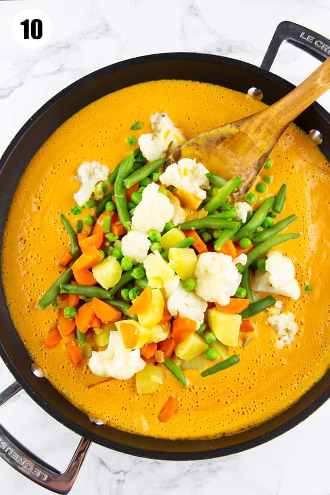 mixed vegetables in a pan with a creamy korma sauce on a marble countertop