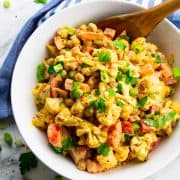 a white bowl with cauliflower salad on a marble countertop