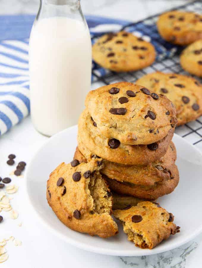 a stack of vegan peanut butter cookies on a white plate with more cookies in the background