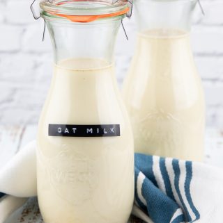 two bottles with homemade oat milk on a wooden countertop