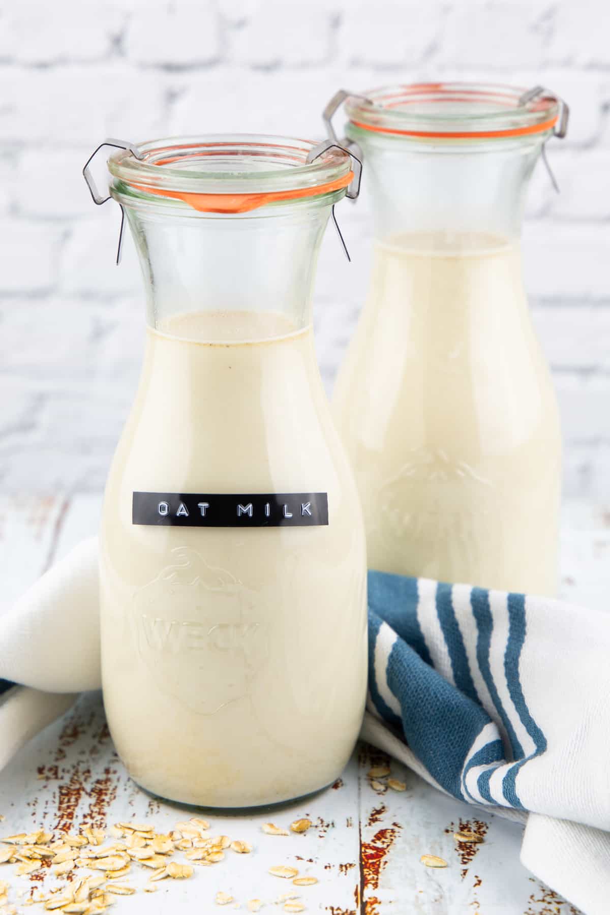 two bottles with homemade oat milk on a wooden countertop 