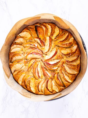 a freshly baked vegan apple cake in a baking pan lined with parchment paper