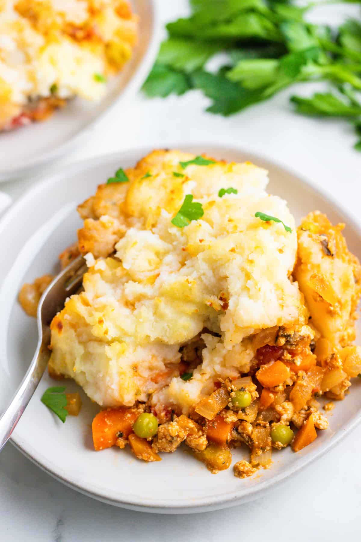 a shepherd's pie on a white plate with a fork on the side 