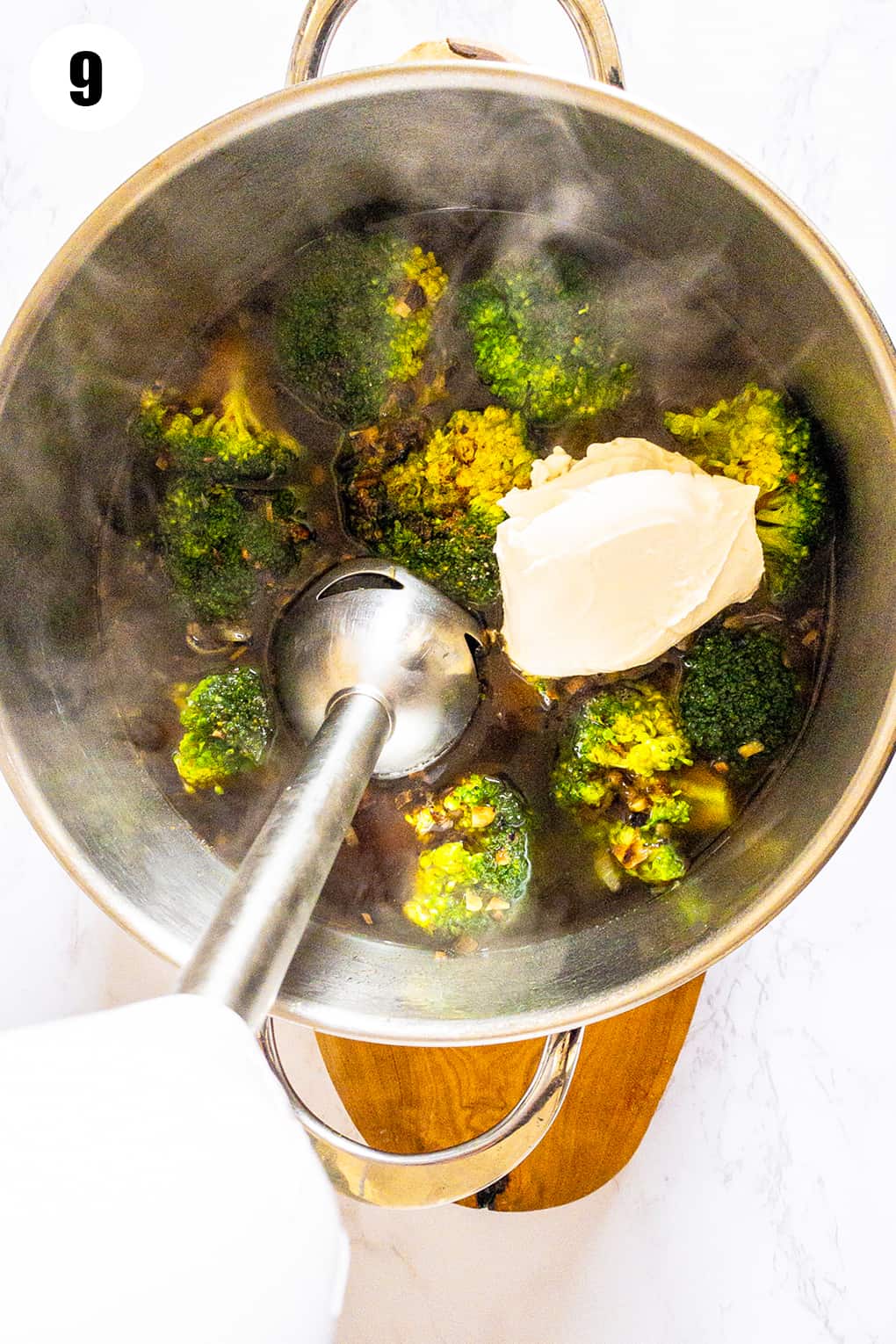 cooked broccoli florets in a pot with an immersion blender
