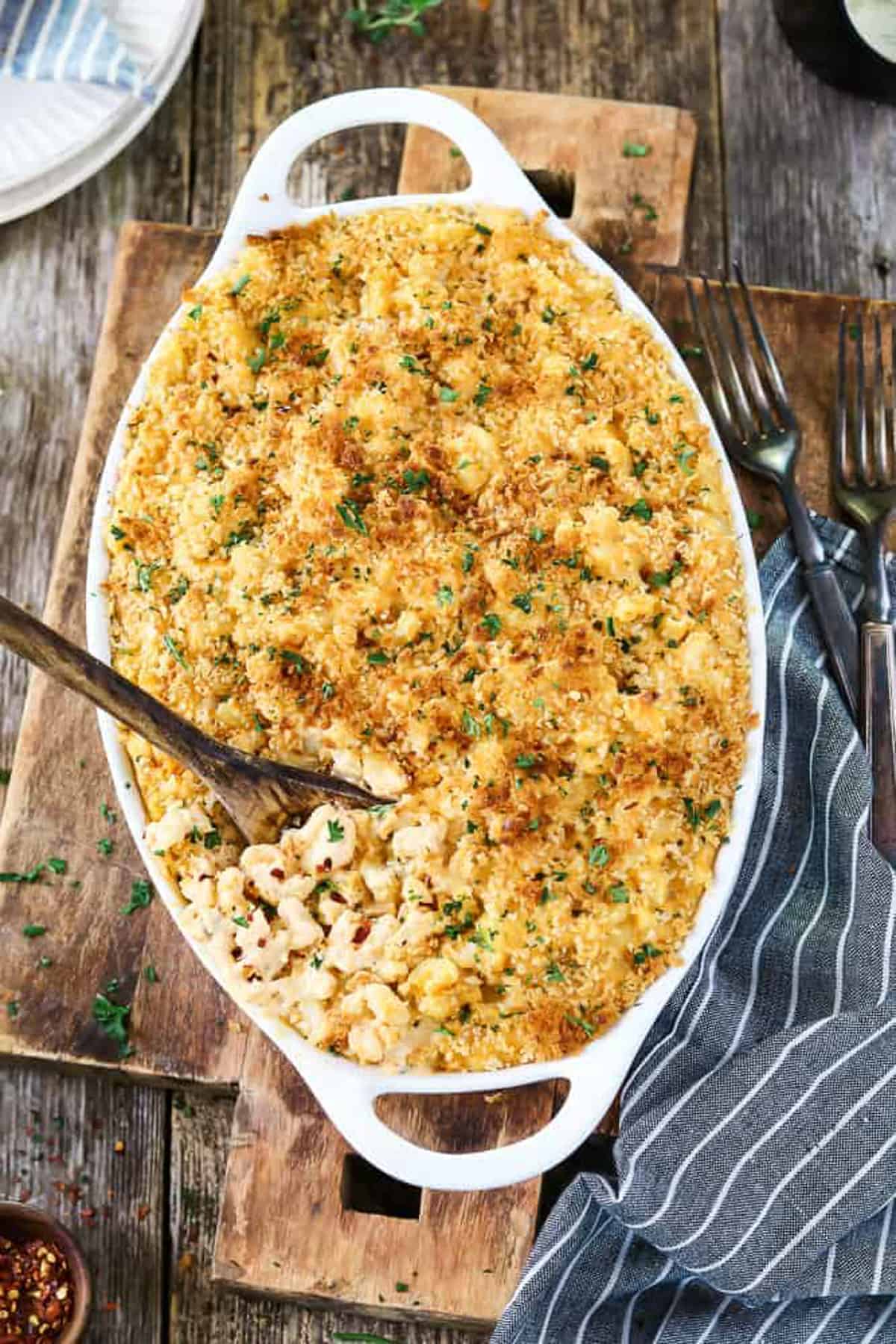 baked vegan mac and cheese in a white casserole dish on a wooden countertop 