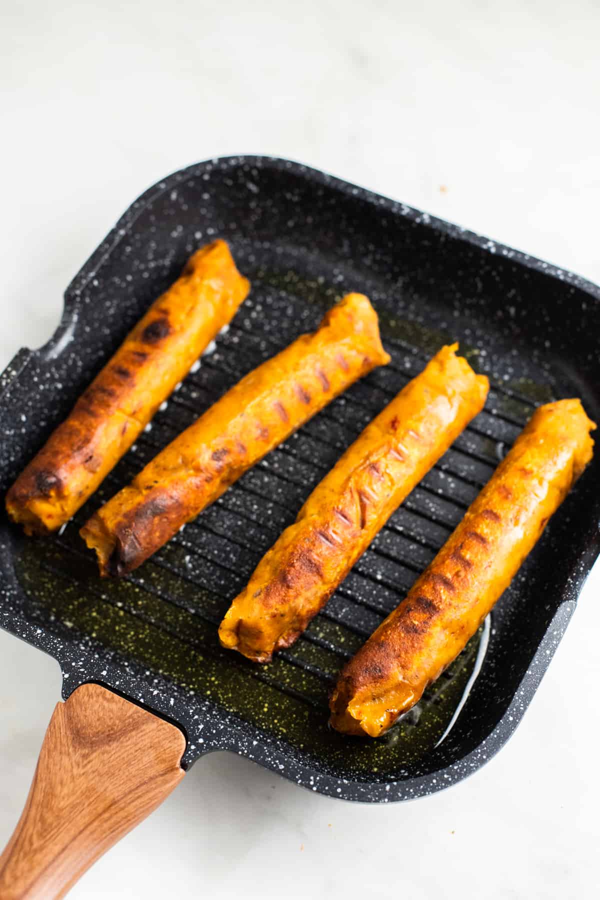 four vegan sausages in a cast iron pan