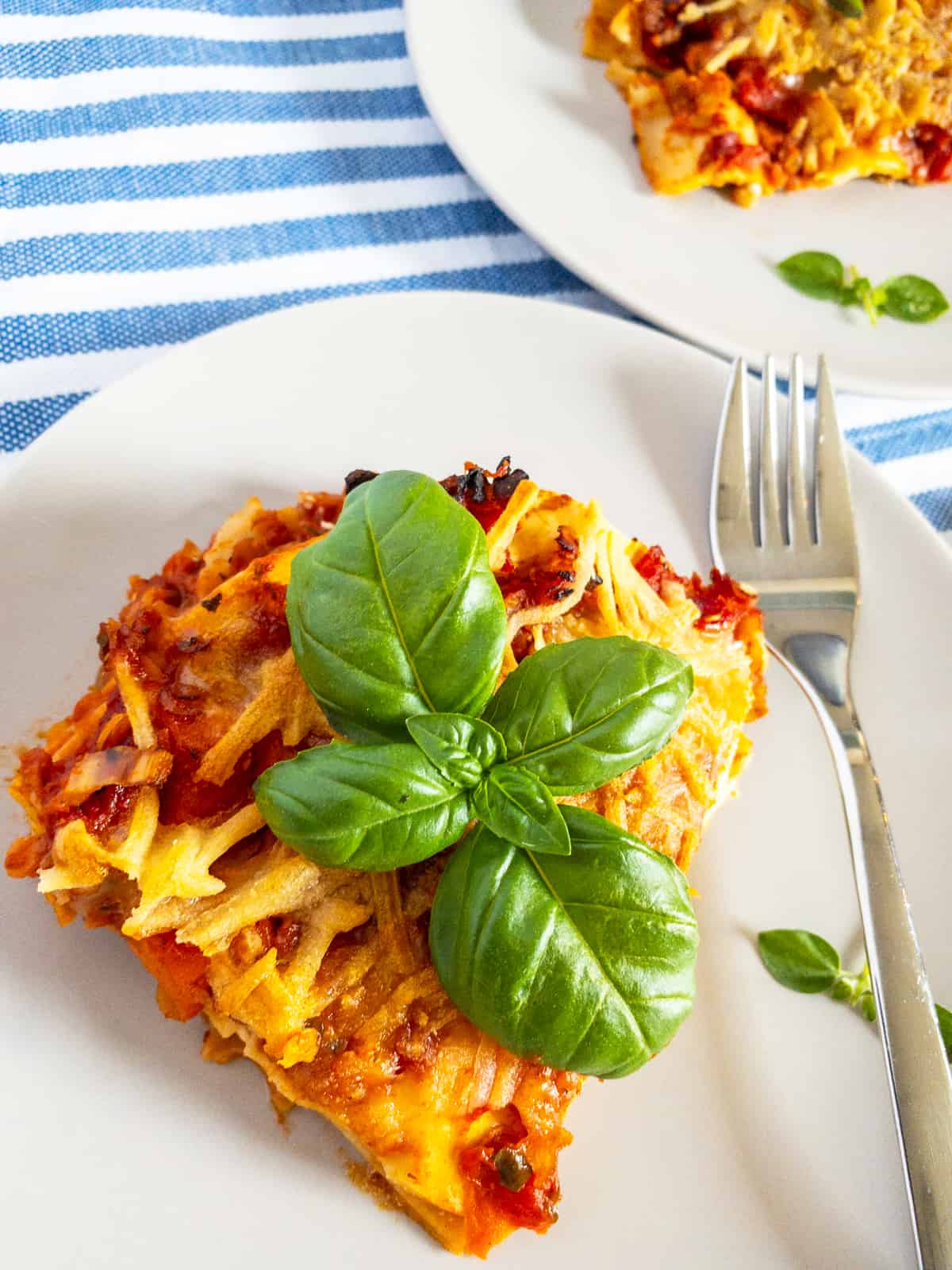 a piece of lasagna on a white plate with a fork on the side