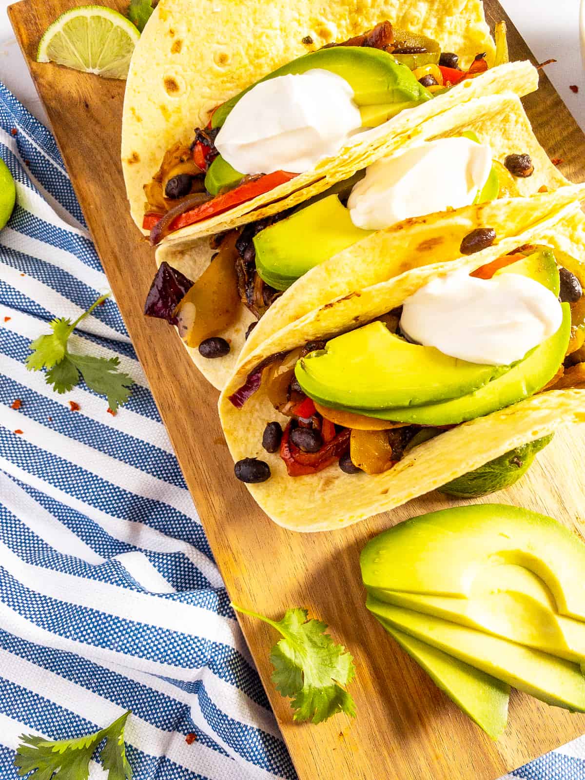 three tortilla wraps filled with vegetarian fajitas on a wooden board