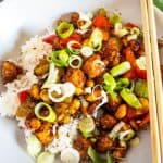 Kung Pao Tofu over rice in a white plate with chop sticks