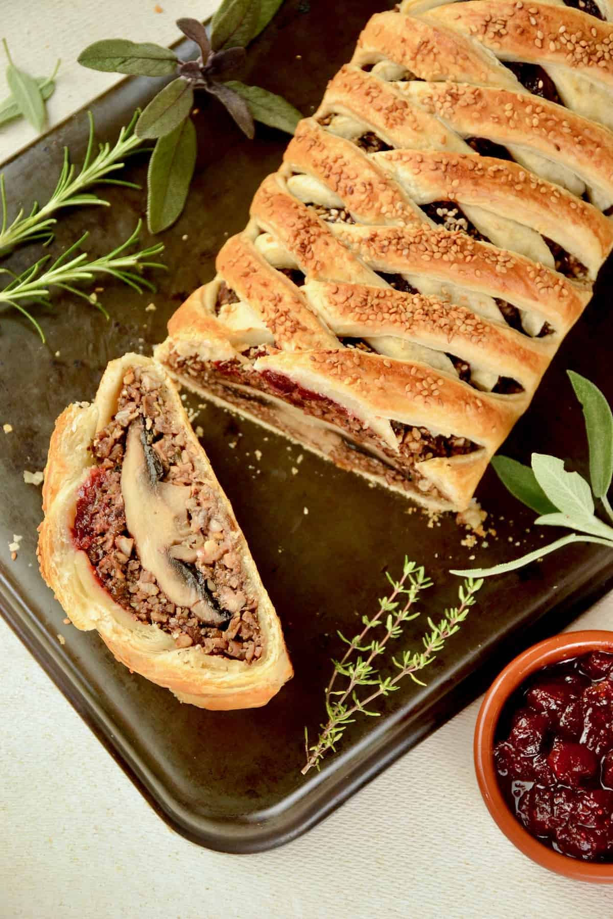 a mushroom Wellington on a cutting board with cranberry sauce on the side