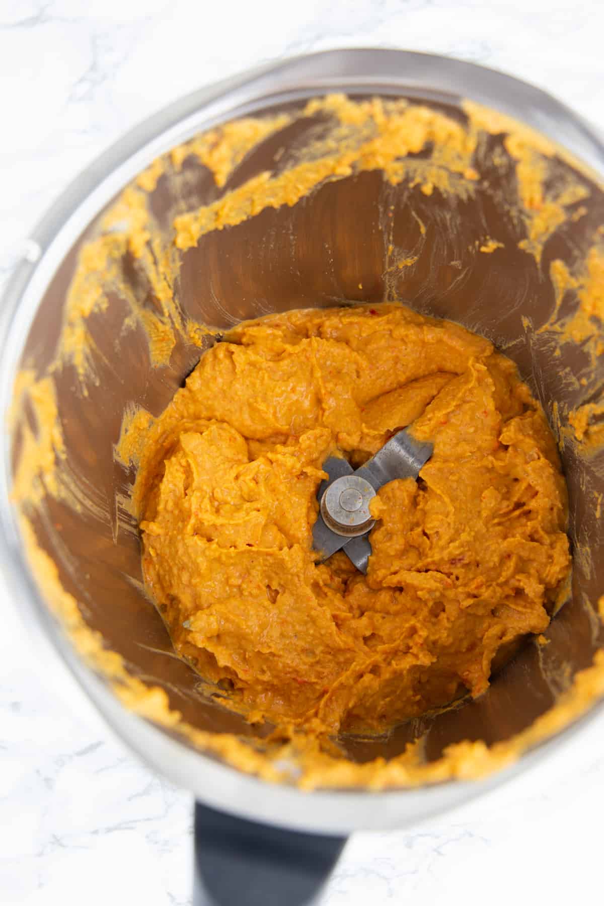 roasted red pepper hummus in a blender on a marble countertop 