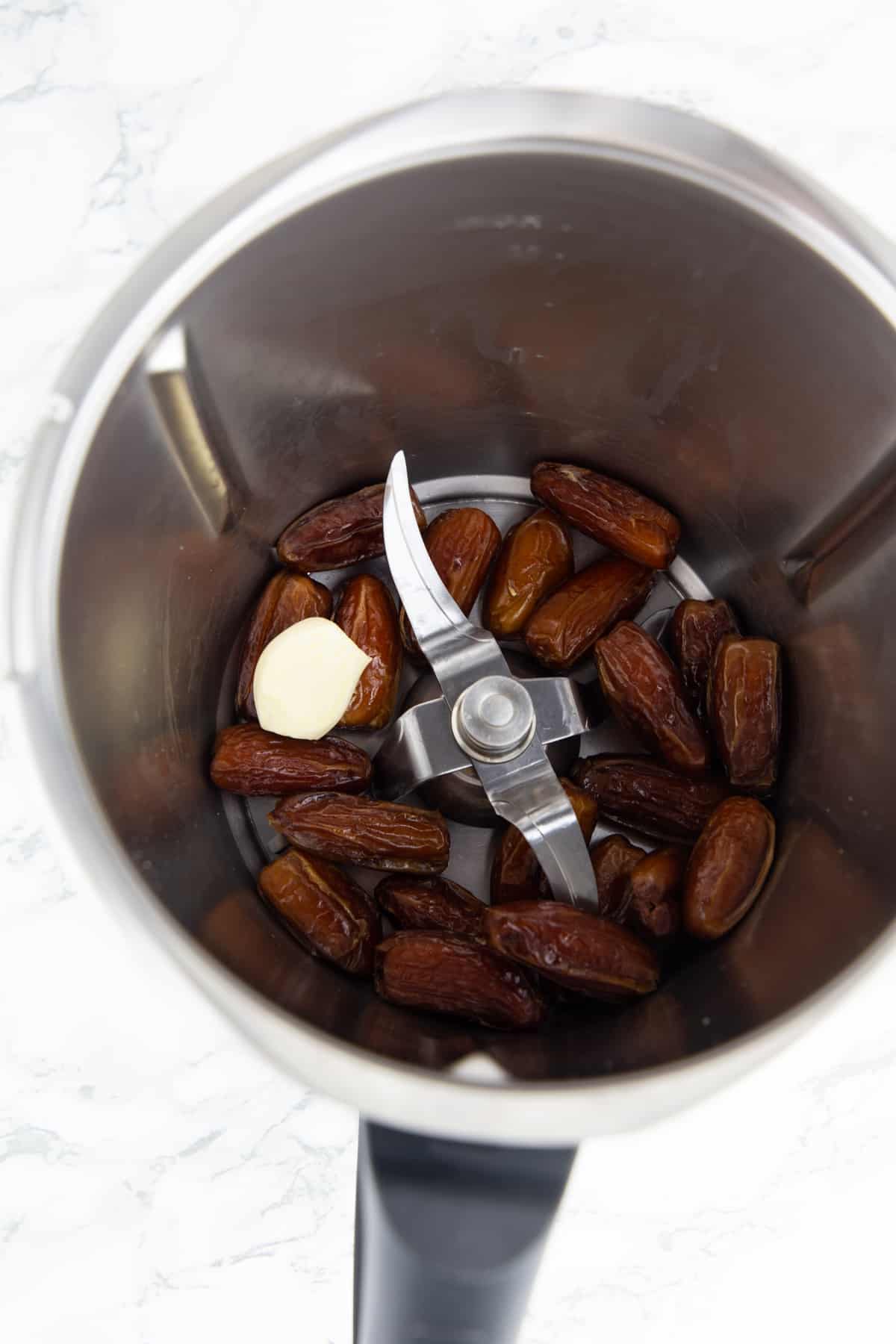 dates in a food processor on a marble countertop 