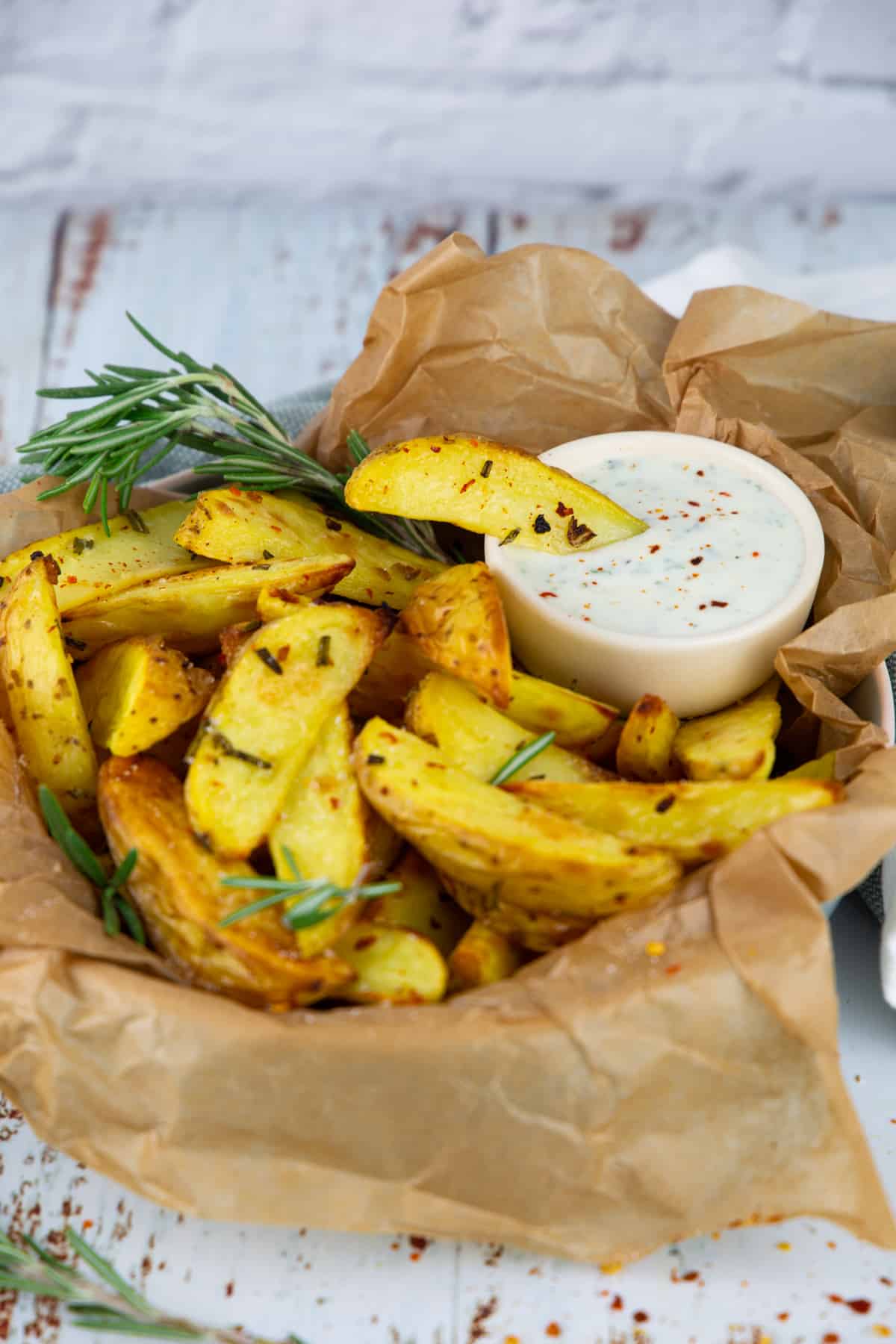 Rosemary potatoes in parchment paper with a small bowl of yogurt dip on the side
