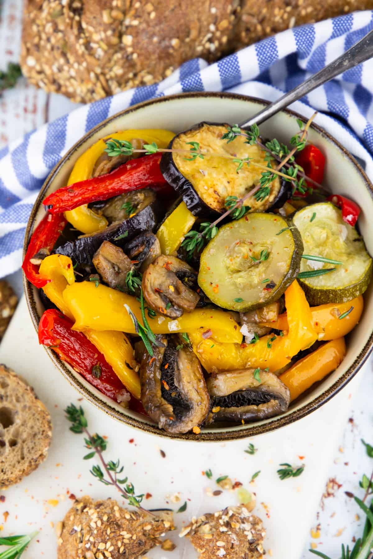 roasted zucchini, bell pepper, eggplant, and mushrooms in a bowl with bread on the side